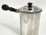 a small silver pot with a handle on a white surface
