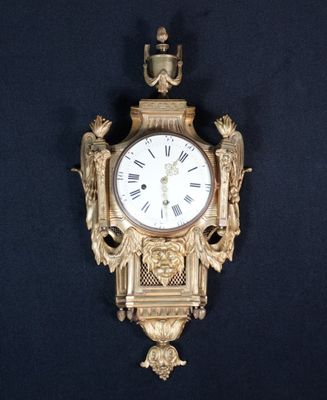 une horloge dorée sur fond noir, ornée d'un oiseau