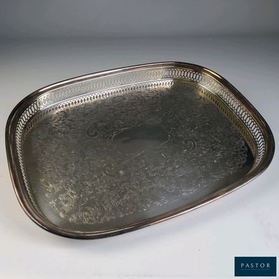 un plateau en argent muni d'une poignée, posé sur une table blanche