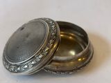 a small silver box with a silver lid on a table