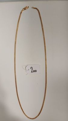 gros plan d'un collier en or sur une surface blanche