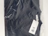 un t-shirt noir dans un sac en plastique, muni d'une étiquette