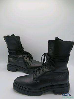 des bottes militaires en cuir noir à lacets et à semelles en caoutchouc, sur fond blanc