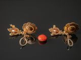 two pairs of gold earrings with coral beads on a black surface