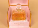an open box with a perfume bottle inside of it on a yellow surface