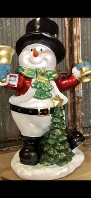 a snowman that is holding a bell and a christmas tree