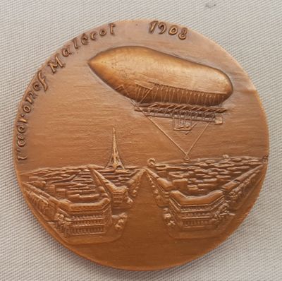 une image représentant une médaille de bronze sur laquelle figure un dirigeable survolant un navire