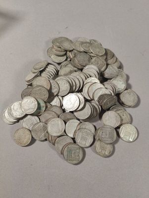 une pile de pièces de monnaie posée sur une table à côté d'un téléphone portable