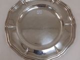 une assiette en argent posée sur une table, sur fond blanc
