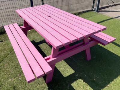 une table de pique-nique rose posée au milieu de la pelouse