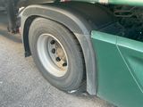 a green semi truck with a flat tire parked on the side of the road