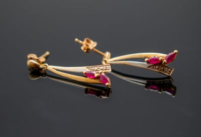 une paire de boucles d'oreilles en or et rubis posées sur une surface noire