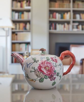 une théière posée sur une table devant une bibliothèque