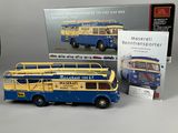 a blue and yellow double decker bus next to a book