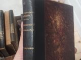a person holding a book in their hand near a pile of books