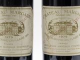 two bottles of red wine sitting next to each other on a white surface