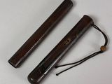 pair of wooden sticks on a white surface with a black cord