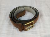 brown leather belt with gold buckle on a white cloth