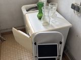 a white table with a green vase on it in a bathroom