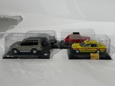 trois petites voitures dans une vitrine posée sur une surface blanche