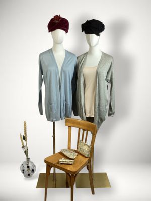 pair of mannequins standing next to a chair and a vase of flowers