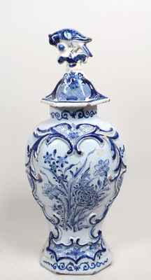 un vase bleu et blanc surmonté d'un oiseau