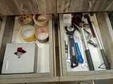 many tools in the drawer of a bathroom cabinet