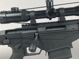the rifle is sitting on a white surface with a red dot on it ' s sight
