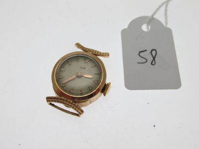 une petite montre-bracelet en or à laquelle est attachée une étiquette
