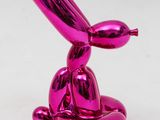 a pink balloon dog sculpture sitting on top of a white surface