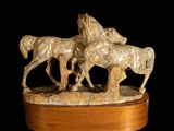 statue of three horses on a wooden base on a black background