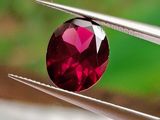 un gros plan d'un diamant rouge tenu par une pince