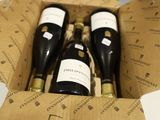 trois bouteilles de vin dans un carton sur une table