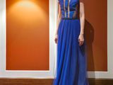 une femme en robe bleue, debout sur un tapis rouge