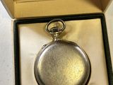 a silver pocket watch inside of a box on a table