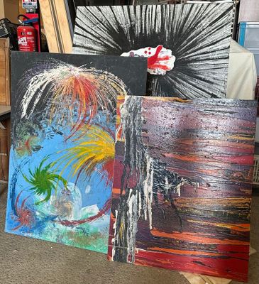 trois tableaux posés par terre les uns à côté des autres