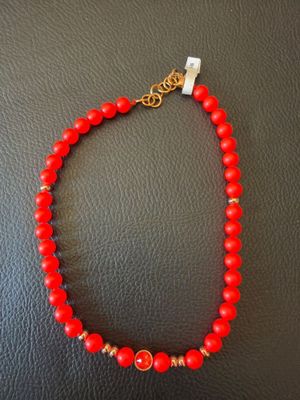 un collier de perles rouges rehaussé de touches dorées sur un fond en cuir noir