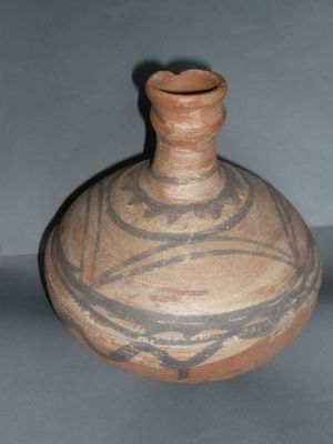 a brown vase with a design on it sitting on a table