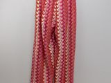 a pink pants hanging on a hanger against a wall