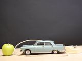 a toy car plugged into an apple on a table