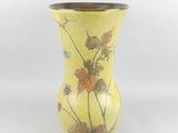 a yellow vase with flowers on it on a white background