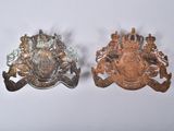 pair of antique brass military badges on a white background