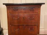 une vieille commode en bois avec un plateau en marbre, posée sur un parquet en bois massif