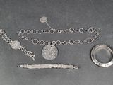 un collier, un bracelet et une bague en argent posés sur une table