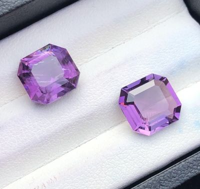 two purple gems in a black box on a white surface