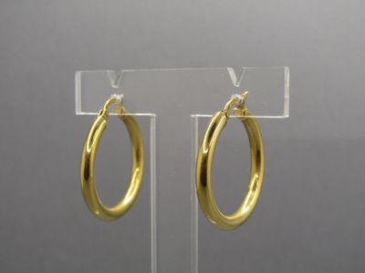 pair of gold hoop earrings on a clear acrylic stand