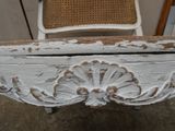 un banc peint en blanc, avec une chaise en osier à côté