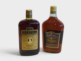 two bottles of whiskey sitting next to each other on a white surface