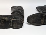 two pairs of black boots that are on a white surface