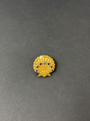 a yellow shell shaped broocher with blue stones on it